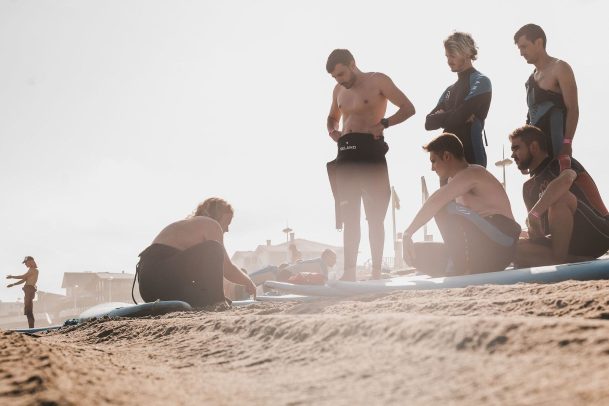 Clases de surf para principiantes con tablas y neoprenos frente al mar